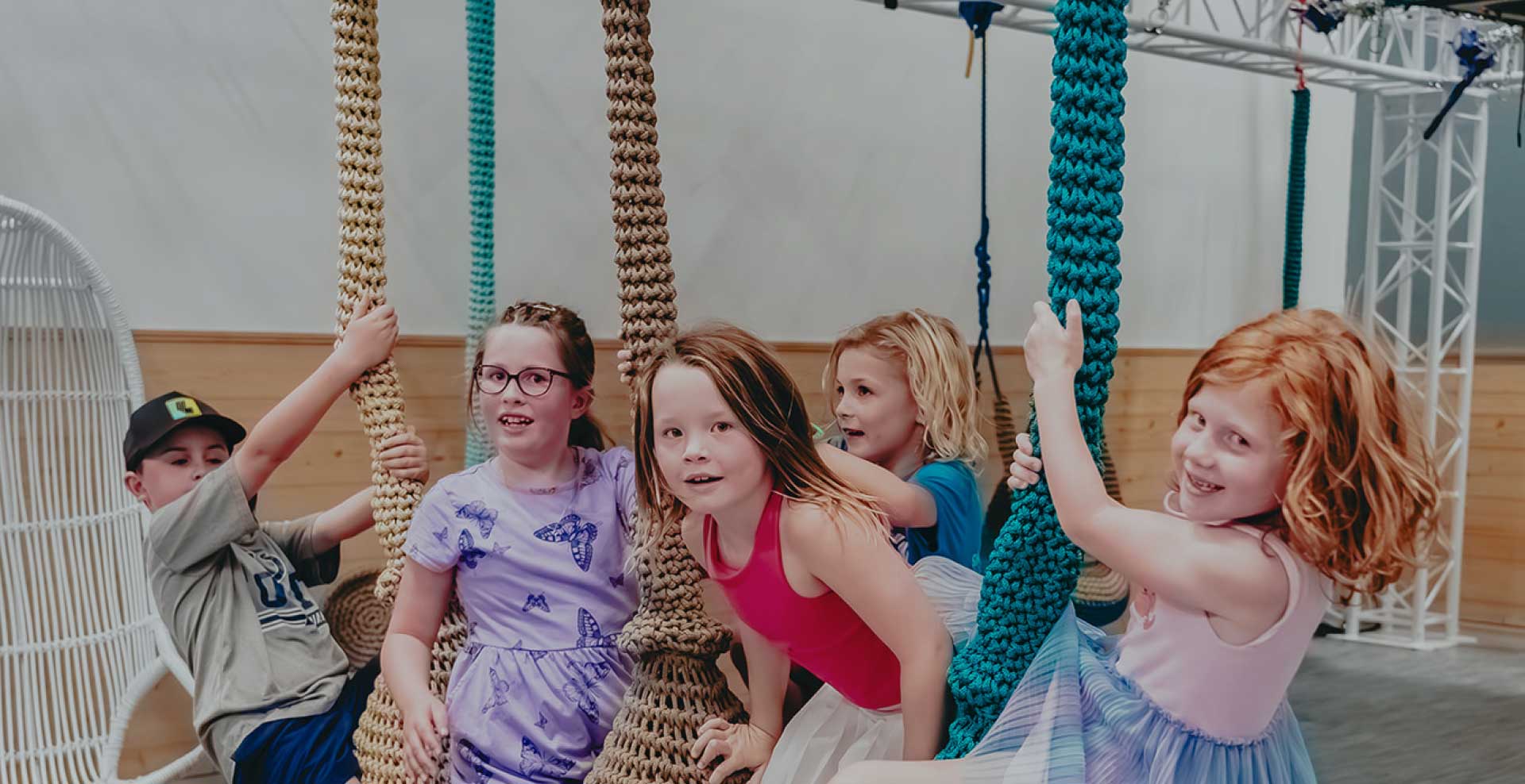 Children playing joyfully on sensory swings at Prana Play in Carmel, Indiana