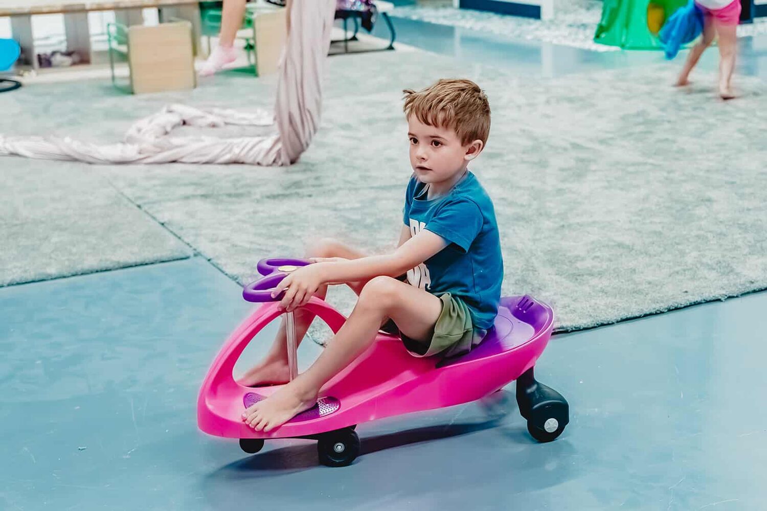 Child riding a play car during open play at Prana Play